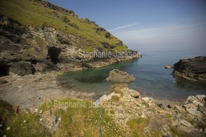 A sheltered bay with a sandy beach lies at the foot of the hill on which the ruins of Tintagel castle stand, in North Devon, England.