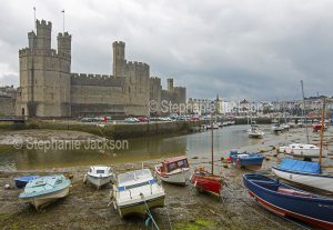 Caernarfon / Carnarvon castle rises about the harbour on the River Seiont in Wales.