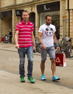 Two men with colourful new shoes walking along a street in Oxford, England