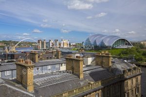 Modern architecture, The Sage Gateshead entertainment centre and millenium bridge beyond the roofs of the British city of Newcastle / Newcastle-upon-Tyne in Northumberland, England.
