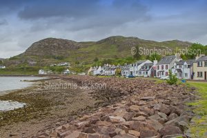The village of Sheildaig sits beside Loch Sheildaig and beside a rocky hill in the Scottish highlands.
