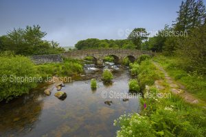 Heritage listed 18th century arched stone bridge over the East Dart, a tributary of the River Dart, in the Dartmoor National Park in Devon, England.