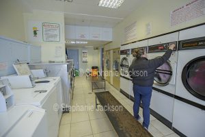 Woman at a washing machine in a laundromat in England.