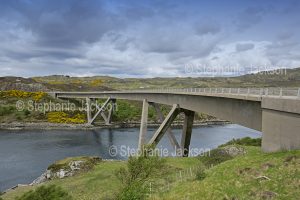 The unique curved Kylesku / Kylescu bridge crosses the lake that's known locally as Loch a’ Chairn Bhain near the village of Kylesku in Scotland.