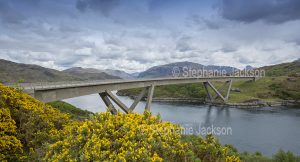 The unique curved Kylesku / Kylescu bridge crosses the lake that's known locally as Loch a’ Chairn Bhain near the village of Kylesku in Scotland.