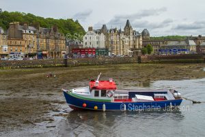 The Scottish town of Oban with a boat in the harbour at low tide.