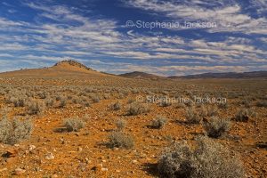 Australian outback landscape with rocky outcrop rising from barren stony plains in the Flinders Ranges region of northern South Australia.