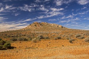 Australian outback landscape with rocky outcrop rising from barren stony ground in the Flinders Ranges region of northern South Australia.