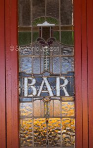 Stained glass window with a sign showing the entrance to the bar of a pub in the Queensland outback town of Charleville.
